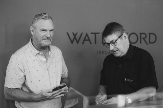 Black and white image of two guests looking at a Waterford display.