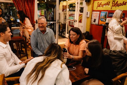 Group of attendees seated around table in pub setting.