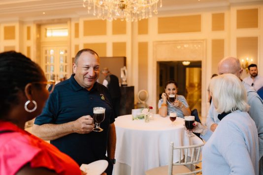 Guests standing with drinks in elegant reception room.