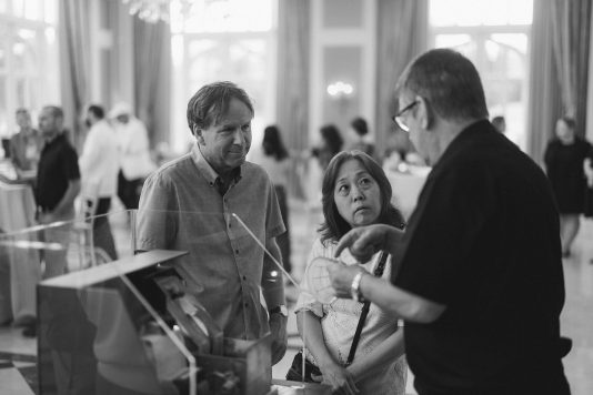 Black-and-white scene of guests chatting.