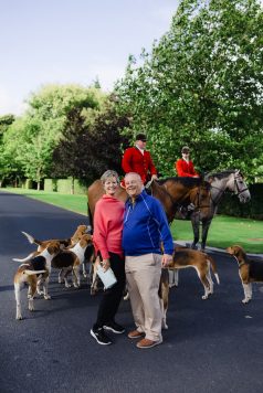 Group gathered with horses and dogs outdoors.