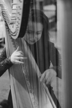 Black-and-white close-up of a harpist playing.