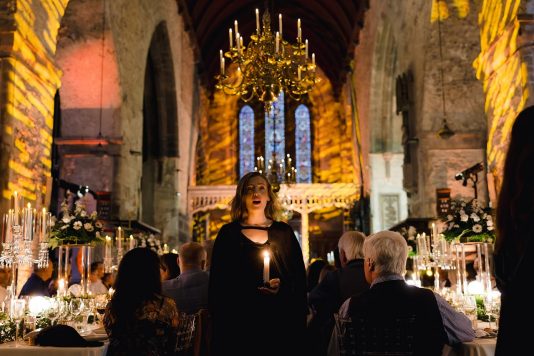 Performer holding a candle and singing during dinner