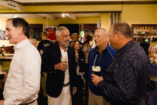 Attendees socializing and holding drinks indoors.