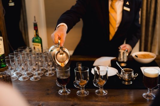 Bartender pouring drinks into multiple glasses.