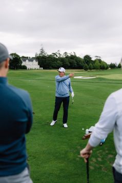 Golfer gesturing while giving instruction on the course.