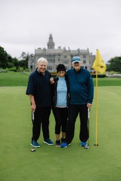 Three guests standing on the golf course.
