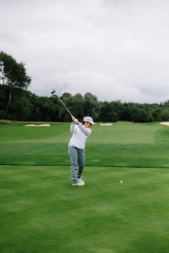 Golfer mid-swing on the tee box.