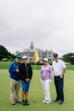 Group posing in front of Adare Manor with a golf flag.