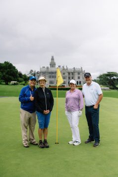 Three guests posing with golf flag on the course.