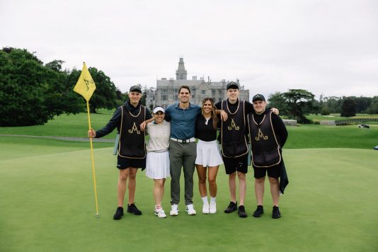 Group of golfers posing with flags and clubs.