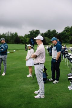 Guests standing beside golf bags on a practice green
