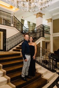 Two guests posing on a staircase indoors.