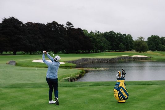 Golfer hitting a shot near a water hazard.