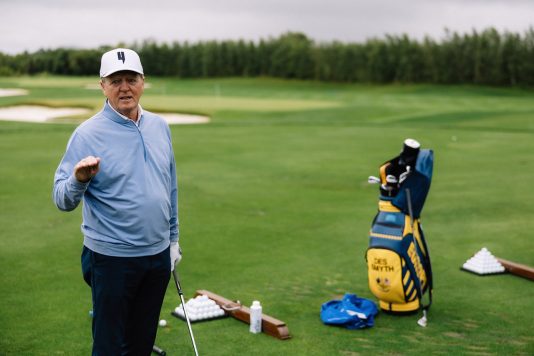 Golfer standing beside clubs and golf bag.