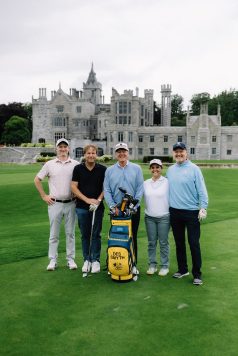 Group posing with golf equipment on the course.