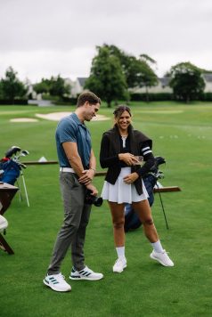 Two guests standing near golf bags and chatting.