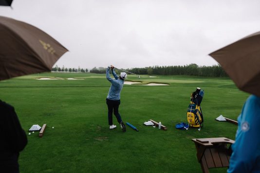 Golfer hitting a ball at the driving range.