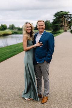 Two guests posing together on a path near water.