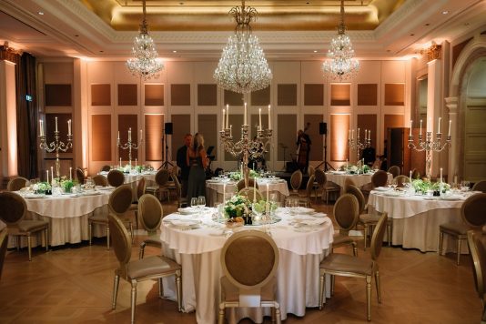 Elegant ballroom setup with round dining tables and chandeliers.
