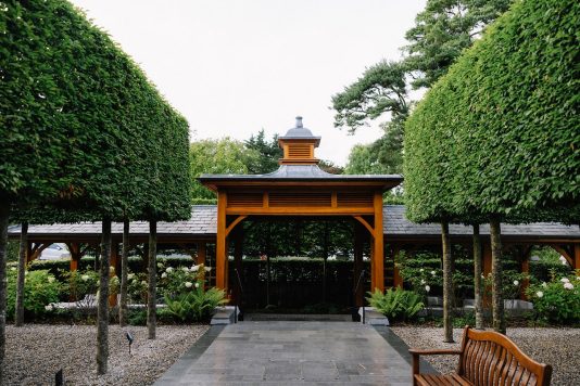 Garden pavilion framed by trimmed hedges.