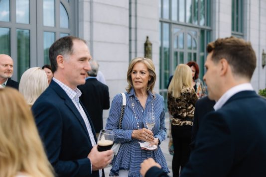 Guests chatting outdoors near a building entrance.