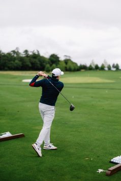 Golfer teeing off with a driver.