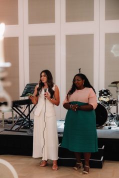 Hosts addressing guests at dinner event.