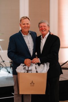 Two guests posing closely while holding gift bags.