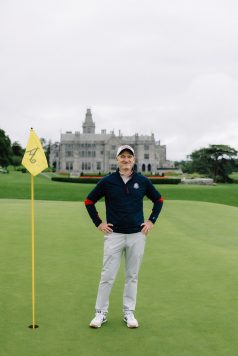 Golfer standing confidently near a flag.