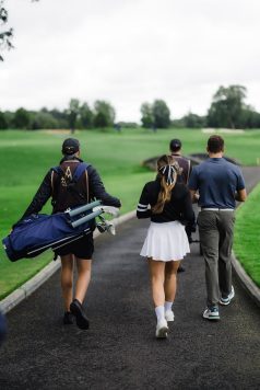 Guests walking carrying golf bags on a path.