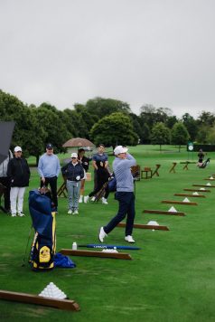 Group of golfers practicing at a driving range.