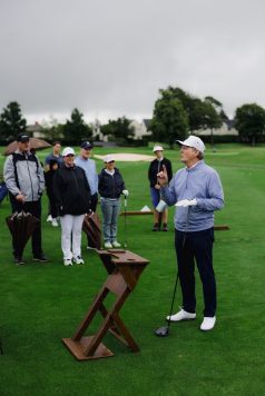 Golfers gathered around practice area.