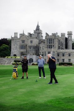 Small group of golfers standing near the manor.