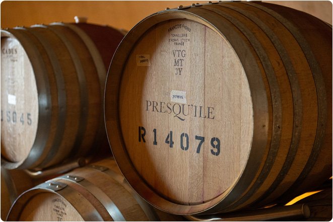 Wooden wine barrels stacked inside a winery cellar