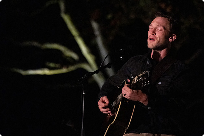 Musician performing on stage while playing a guitar