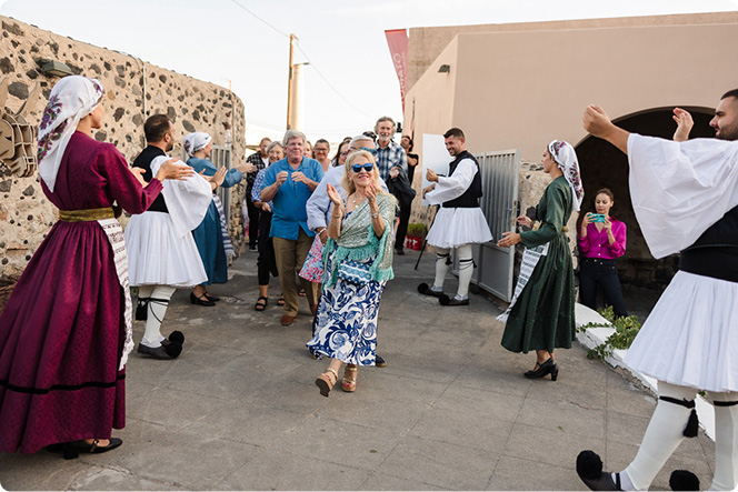 Group gathered outdoors watching traditional dancers perform at a local celebration
