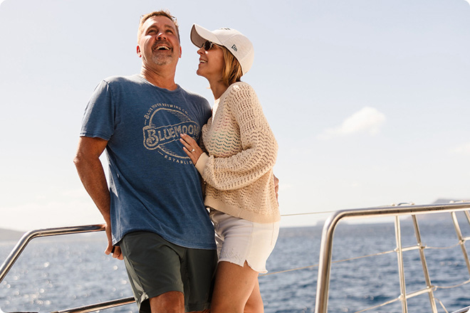 Two people standing on a boat deck with ocean views in the background