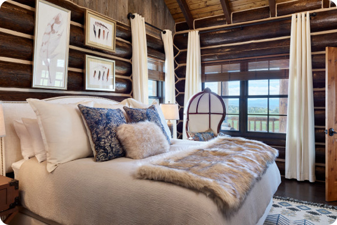 Rustic luxury bedroom with wooden walls, large bed, and windows overlooking a mountain landscape
