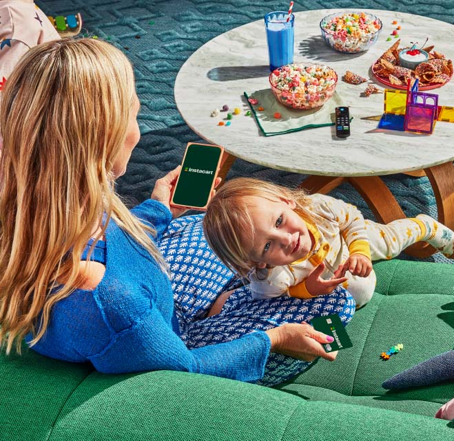 Mother and daughter eating snacks while holding Instacart credit card